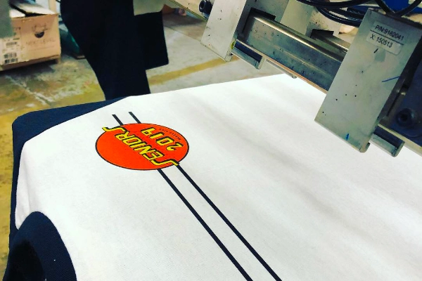 Screen-printing press in action printing a class-of-2019 design on a white tee
